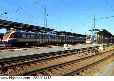 Passenger Trains With Railway Carriages Stands On The Platform Of The Station. Travel And Tourism Co