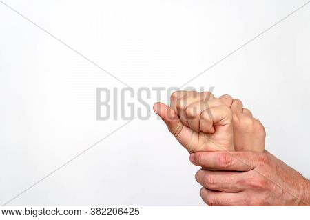 Mans Hand Clenches Small Childrens Hands In A Fist A White Background. Human Trafficking And Interna