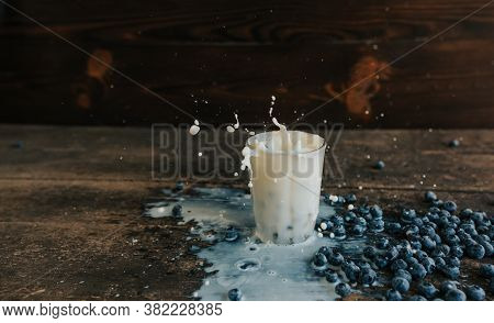 Berries Are Thrown Into The Transparent Glass Making Splashes Of Milk
