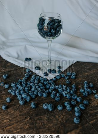Blueberries Filled In A Transparent Glass And Scattered