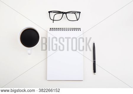 White Notepad With Black Pen And Glasses On Light Table,