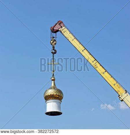The Dome Of A Christian Temple Hangs On The Hook Of A Crane. Building Or Dismantling A Church Agains