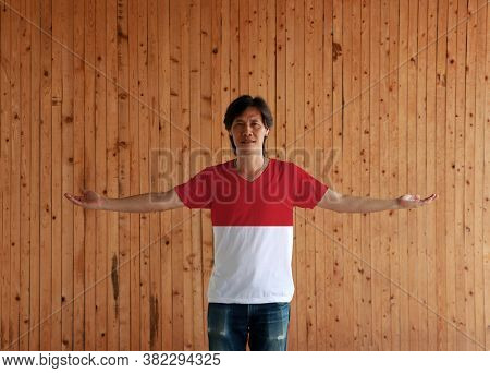Man Wearing Monaco Flag Color Shirt And Standing With Arms Wide Open On The Wooden Wall Background, 