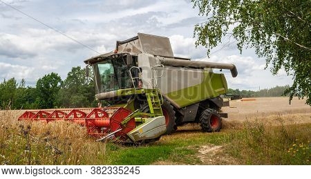 Modern Harvester At Work In Field During Wheat Harvesting Season On Sunny Day. Reaping Machines Harv