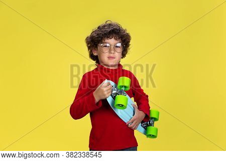 Skaterboy. Portrait Of Pretty Young Curly Boy In Red Wear On Yellow Studio Background. Childhood, Ex