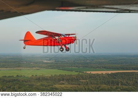 Vintage Red Small Plane Stinson In Flight Over The Green Forest.