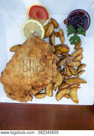 Feldkirch, Austria - July 26, 2020: Breaded Cordon Bleu Steak Served With Baked Potatoes, Cranberry 