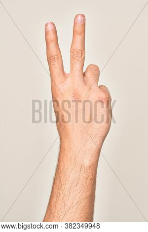 Hand of caucasian young man showing fingers over isolated white background counting number 2 showing two fingers, gesturing victory and winner symbol