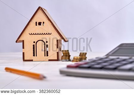 House Cost Evaluation Concept. Calculating Money And Buying Hose. Miniature Wooden House With Calcul