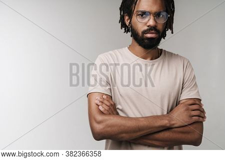 Image of concetrated african guy posing isolated over grey wall background in eyeglasses