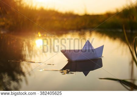 A Paper Boat Floats On The Water At Dawn. Creative Concept Of Outdoor Recreation, River, Travel. Coz