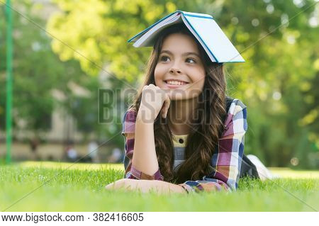 This Is My Reading House. Happy Child Hold Book On Head Lying On Green Grass. Lending Library. Readi