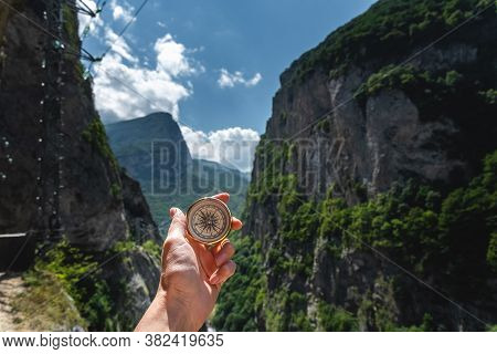 First-person View Of A Female Hand With A Compass On A Background Of A Beautiful Mountain Landscape.