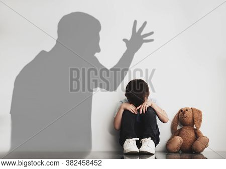 Child Abuse. Father Yelling At His Son. Shadow Of Man On Wall