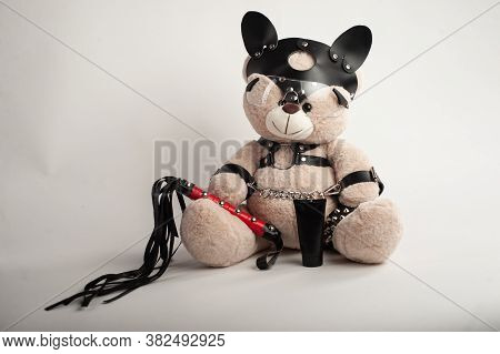 Toy Bear Dressed In Leather Belts Harness Accessory For Bdsm Games On A Light Background