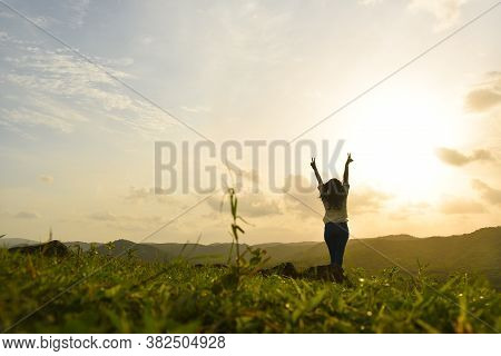 Beautiful Woman In A White Dress Embracing The Golden Sunshine Glow Of Sunset With Her Arms Outsprea