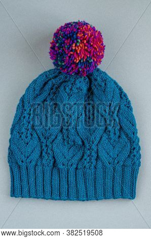 Beautiful Kace Handknitted Hat With Multicolored Pompon On Gray Background. Top View