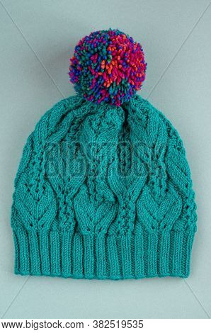 Beautiful Kace Handknitted Hat With Multicolored Pompon On Gray Background. Top View