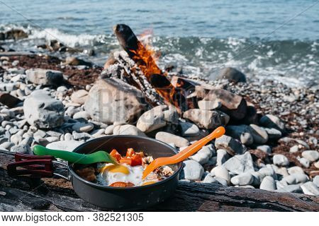 Eat Fried Eggs From A Frying Pan On The Beach, A Delicious And Healthy Breakfast In A Camping In The