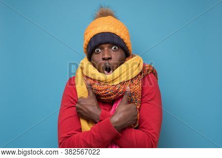 Funny African American Man In Yellow Scarf And Hat Freezing In Warm Clothing.