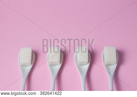 Sugar Cubes On A Pink Background. Sugarcubes Lie On Spoons. Spoons With Sugar Are In A Row