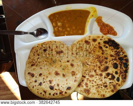 A Plate Full Of Hot And Crispy Aloo Paratha Served With Spicy Pickle.