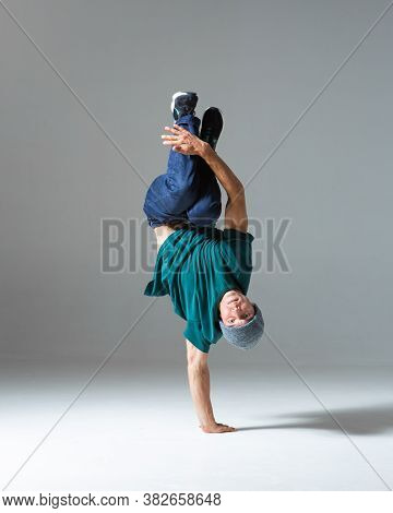 Cool Guy Breakdancer Stands On One Hand Dancing Lower Break Dance Isolated On Gray Background. Break