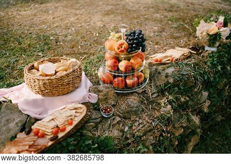 Whatnot With Fruit, A Basket With Slices Of Bread And A Board With Cheese And Meat Cuts On Stones In