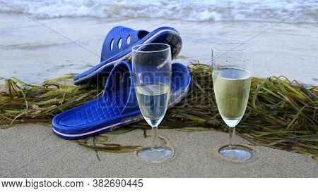 Sellin, Deutschland, Germany\n07.07.2020\nchampagne Glasses And Bathing Shoes On A Sandy Beach On Se