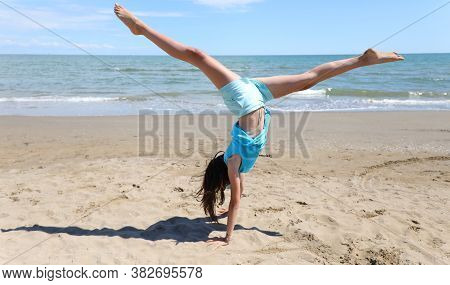 Girl Does Gymnastics On The Beach With A Pirouette And Legs In The Air