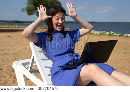 Girl Greeting During Videocall On Laptop Sitting In On The Beach. Freelancer And Blogger Participate