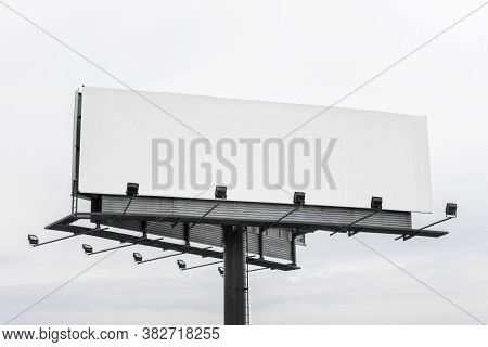 Large Mega Board, Commercial Billboard With Empty Blank Space And Light On Gray Sky Background.