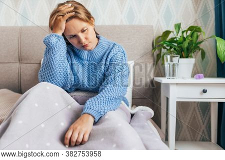 Young Blonde Woman Suffering Of Depression Sitting N Bed On In Warm Sweater. Loneliness, Sadness, Di
