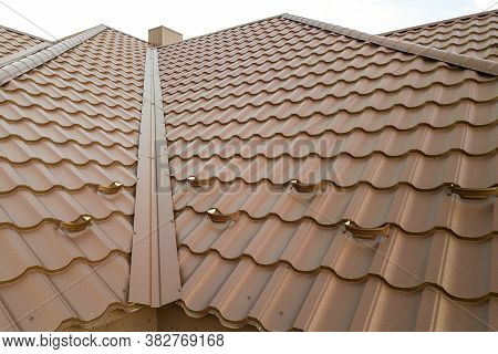 Detail Of A House Roof Surface Covered With Brown Metal Tile Sheets.