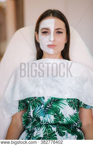 Beautiful Woman With White Mask On Hulf Of Face. Attractive Brunrtte Woman In Beauty Salon
