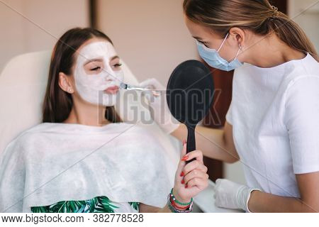 Cosmetologys Specialist Applying White Facial Mask Using Brush. Making Skin Hydrated And Face Glowin