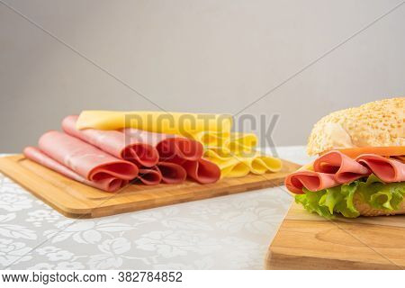 Mortadella Sandwich, Lettuce, Tomato And Cheese On A Polished Board And Slices Of Mortadella And Che