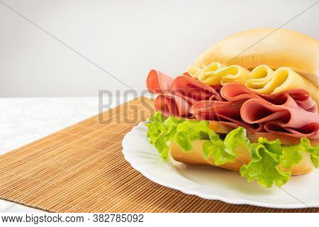 Mortadella Sandwich, Lettuce And Cheese On A White Plate And A Bamboo Mat With White Background On A