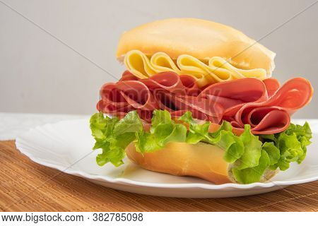 Mortadella Sandwich, Lettuce And Cheese On A White Plate And A Bamboo Mat With White Background On A
