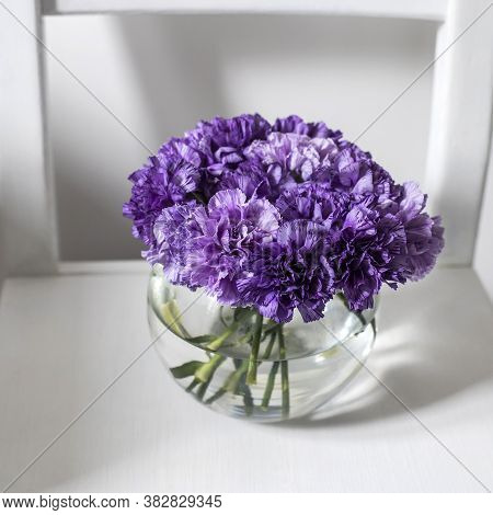 Bridal Bouquet Of Lilac Carnations In A Round Glass Vase As Decoration In White Interior