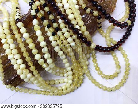 Many Baltic Amber Round Beads Lie On A Large Piece Of Natural Amber. Template For Decorating A Jewel