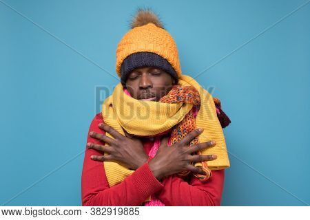 Funny African American Man In Yellow Scarf And Hat Freezing In Warm Clothing.