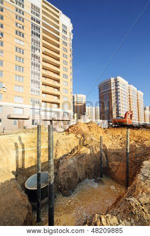 หลุมสำหรับ sewerage น้ำสกปรกใกล้เหลืองอาคารสูงอาคารกำลังก่อสร้างที่ซันนี่