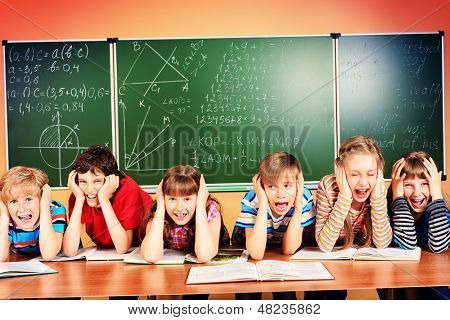 Grupo de crianças de escola cansadas em um grabing de sala de aula suas cabeças. Educação.
