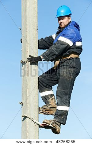 Electrician lineman repairman worker at climbing work on electric post power pole