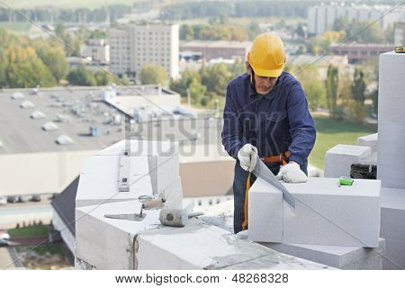 bricklayer ผู้ปฏิบัติงาน mason ก่อสร้างทำงานกับอิฐหินปูน ด้วย putty พลั่วมีดกลางแจ้ง