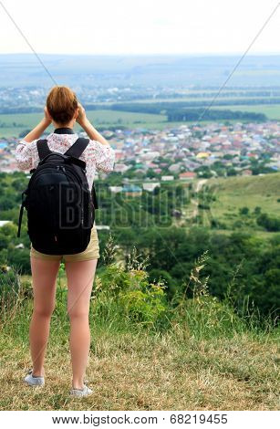 young woman hiking watching through binoculars