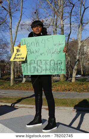 A protester holds a sign against police brutality and grand jury decision on Eric Garner case
