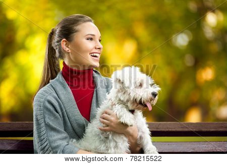 Smiling young woman with maltezer dog out in the park