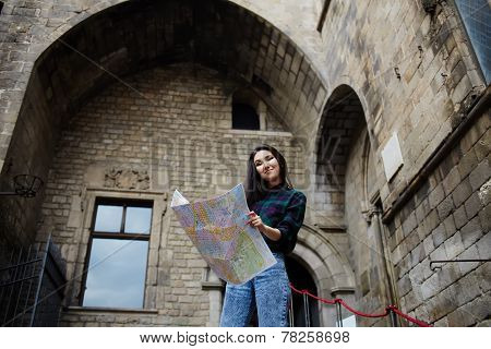 Young tourist girl holding city map in the hands smiling charming girl studying city map